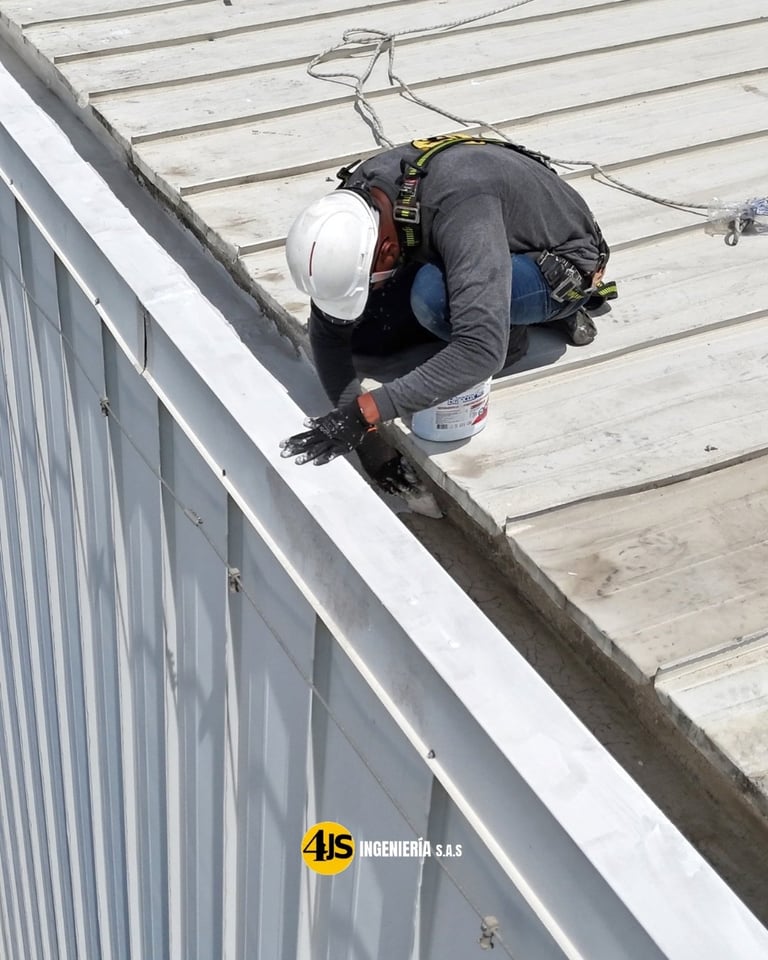 Construction worker in white hard hat and safety harness working on a sloped metal roof with wooden decking