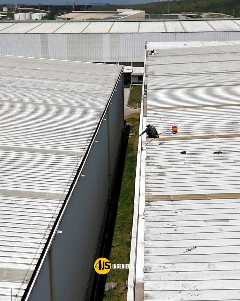 Aerial view of corrugated metal industrial roofing with gap and yellow JS Ingenier company logo visible