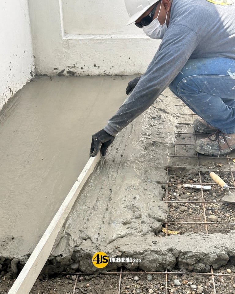 Construction worker in mask and gloves spreading concrete with a trowel on a floor foundation